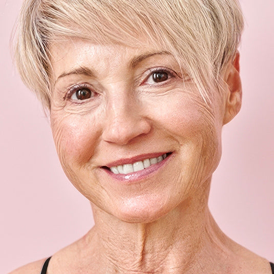 Close-up of a woman with short blonde hair against a pink background