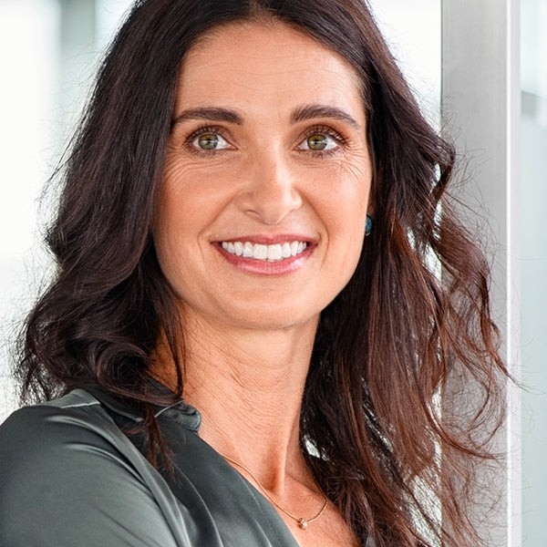 Woman with long dark hair smiling against a neutral background