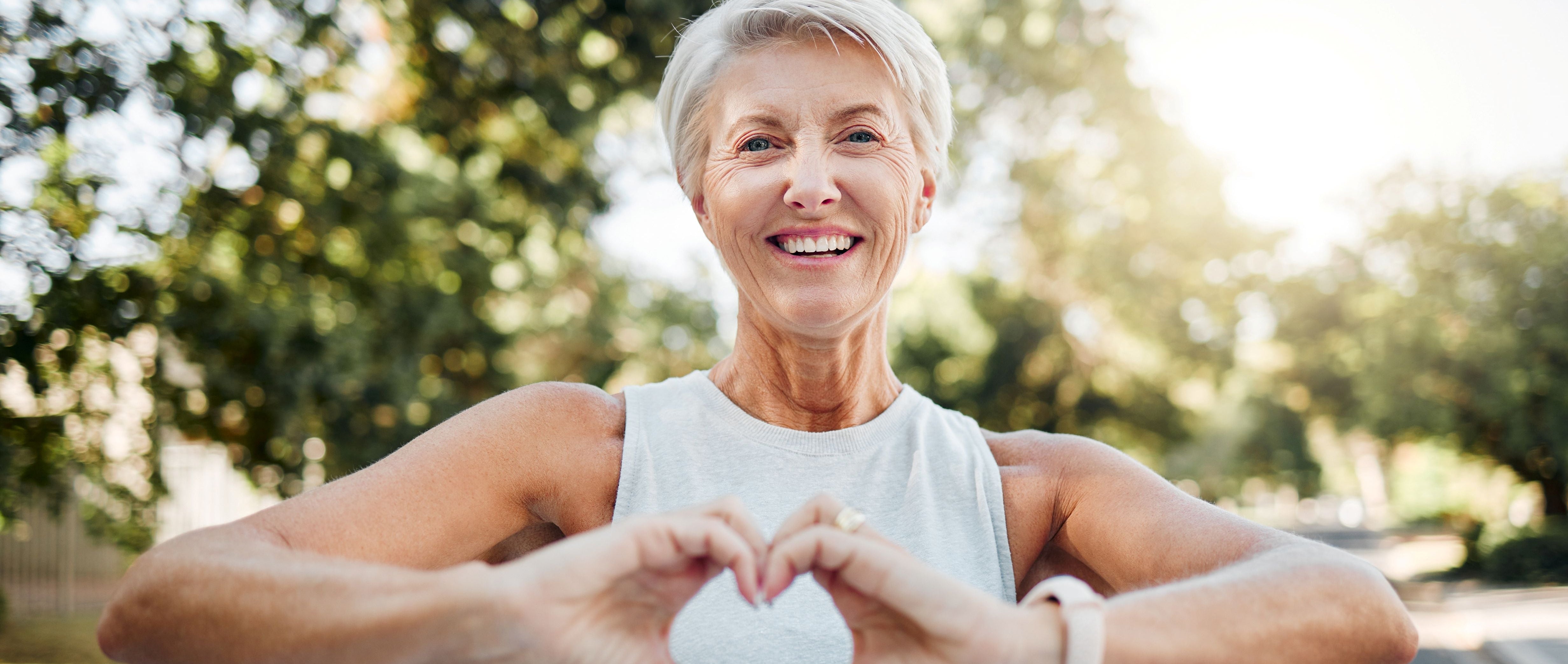 Woman making a heart shape with her hands outdoors