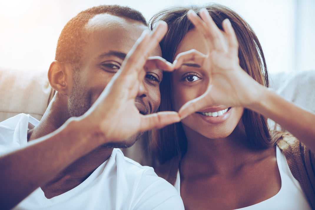 Couple making heart shapes with their hands in a bright room