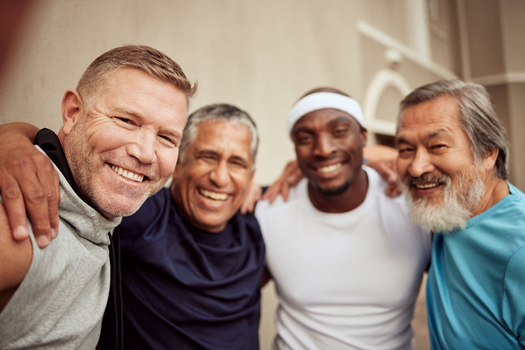 Four men posing together outdoors, smiling and embracing each other.