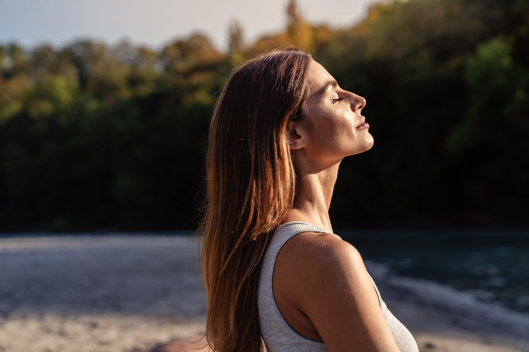 Woman with long hair standing on a beach with trees in the background