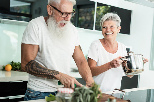 Two elderly people in a kitchen preparing food.